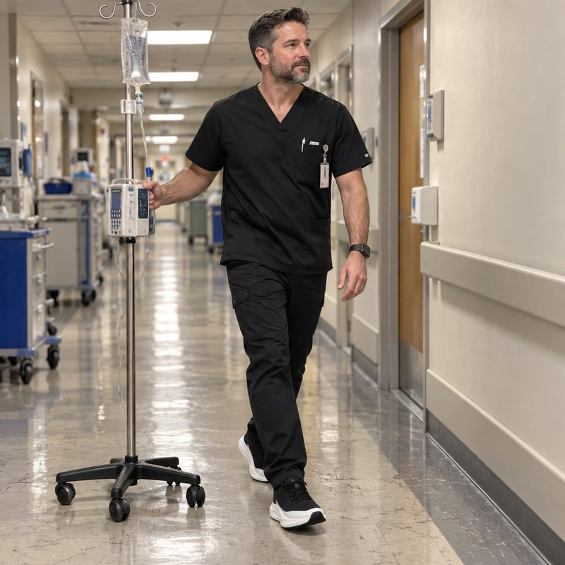 Nurse walking a hospital corridor beside an IV pole