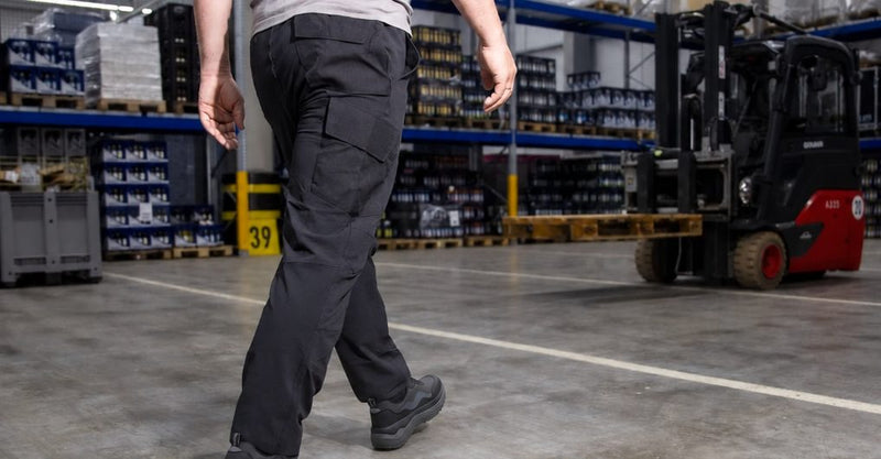 Worker walking down a warehouse aisle past a forklift